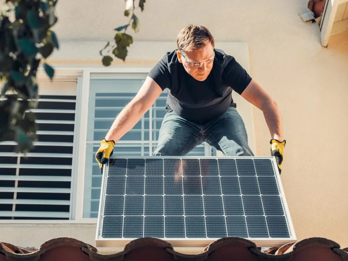 Installateur posant un panneau solaire sur un toit en tuiles