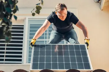 Installateur posant un panneau solaire sur un toit en tuiles